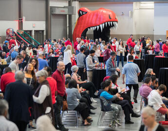 A group of people in a room with a large Dino head in the background