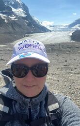 A woman takes a selfie in front of a glacier